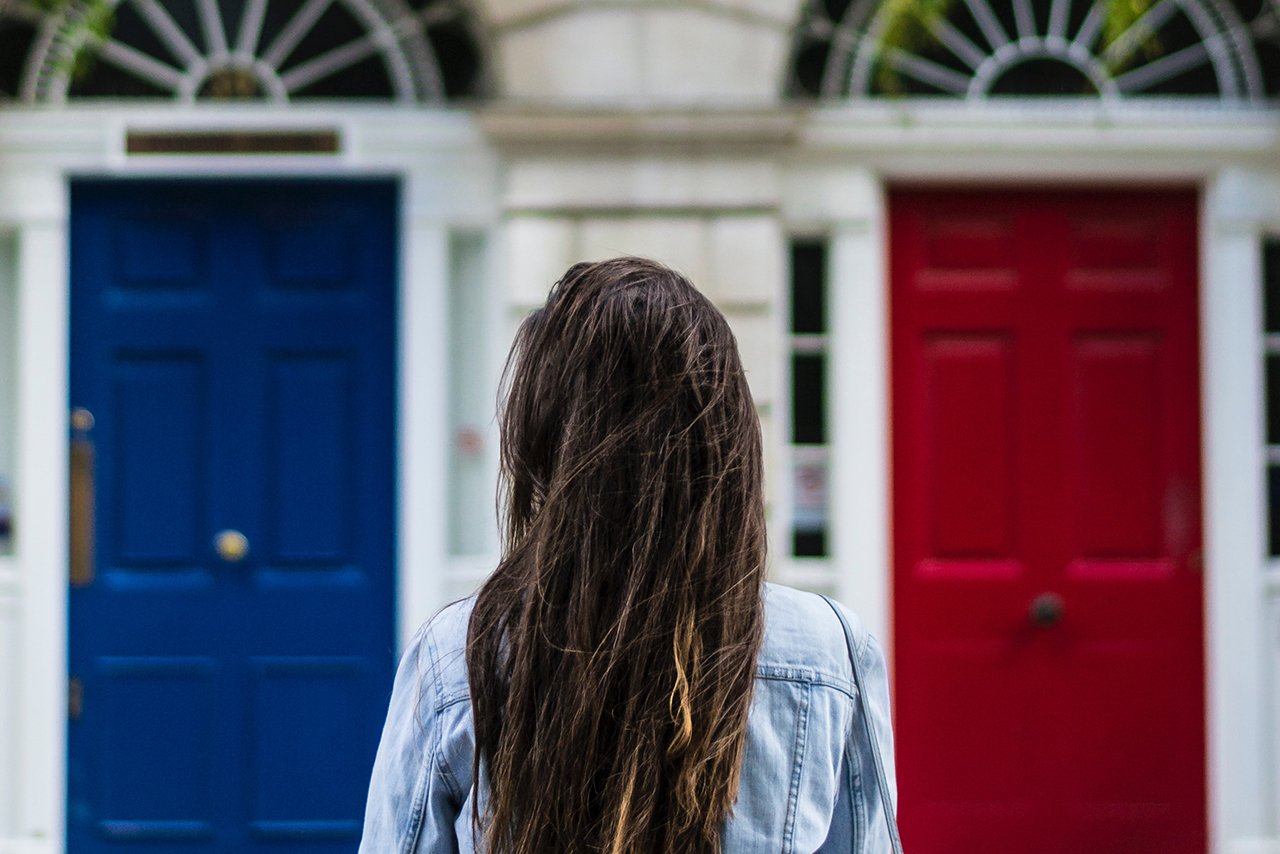 赤と青の扉の前に立つ女性